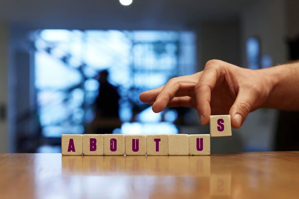 A person is stacking blocks with the word " about us ".